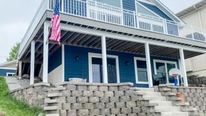 A two-story house with a stone retaining wall and a balcony.