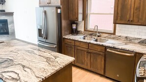 A modern kitchen with wooden cabinets, a granite countertop, and a built-in dishwasher.