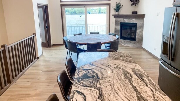 A spacious kitchen with a large island, a fireplace, and a view of a lake through the sliding glass doors.