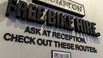 Een bord aan de muur met 'FREE BIKE HIRE' en een QR-code.