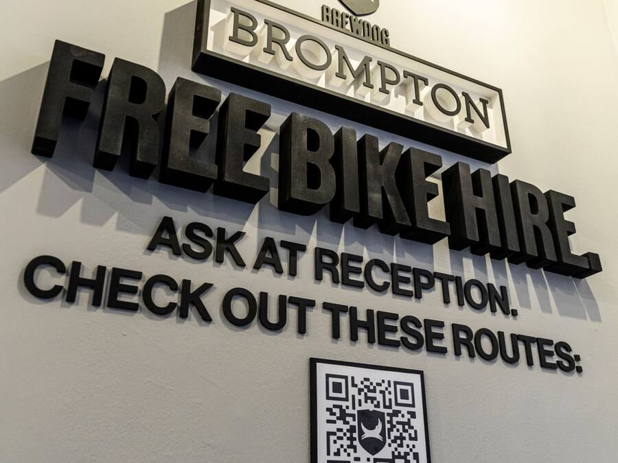 Een bord aan de muur met 'FREE BIKE HIRE' en een QR-code.