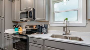 Een koelkast, een microgolfoven, kookgerei, borden en bestek