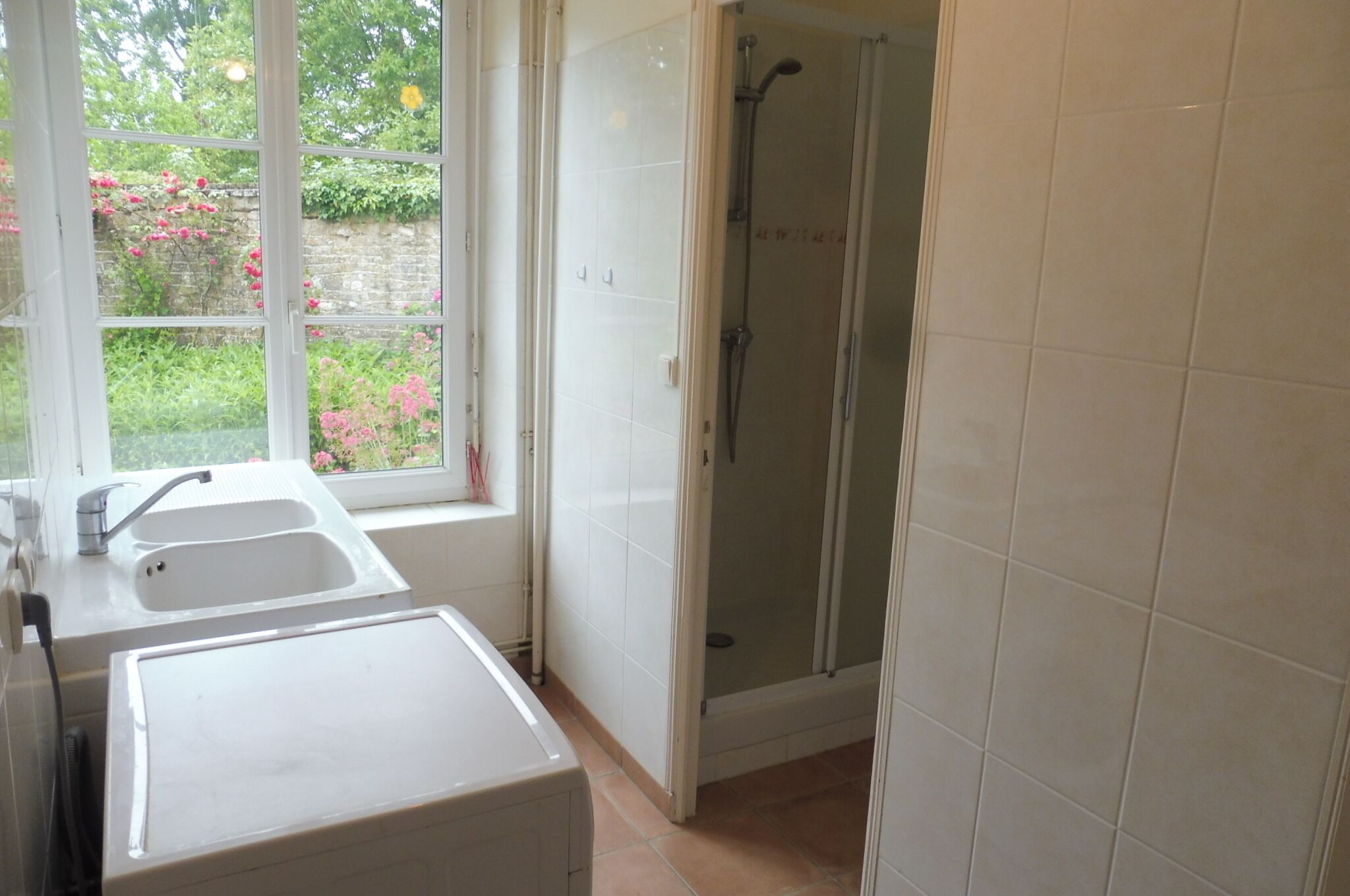Ein Badezimmer mit Dusche, Waschbecken und Fenster.