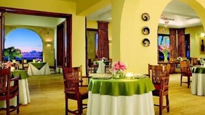 A dining area with round tables, chairs, and a view of the outdoors. - Golden Bear Lodge and Spa (Punta Cana)