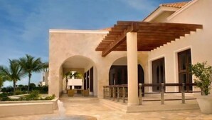 A building with a covered outdoor area, a fountain, and palm trees in the background. - Golden Bear Lodge and Spa (Punta Cana)