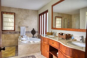 A bathroom with a bathtub, two sinks, a large mirror, and a vanity with wooden cabinets. - Golden Bear Lodge and Spa (Punta Cana)