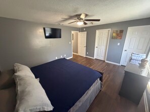 Une chambre à coucher avec un lit, un ventilateur de plafond et une porte donnant sur une autre pièce.
