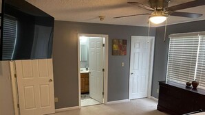A bedroom with a bed, a dresser, a ceiling fan, and a door leading to a bathroom. - Beautiful Private 3 Bedroom Home (Albany)