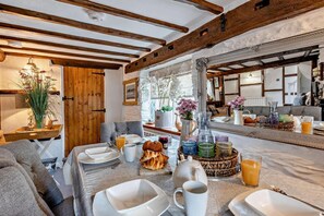 Un comedor acogedor con vigas de madera, una mesa dispuesta para el desayuno y vista al salón.
