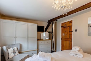 A bedroom with a large wardrobe, a vanity with a mirror, a chandelier, and a wooden door.