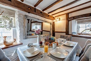 A dining area with a table set for four, a mirror, and a window with a view.