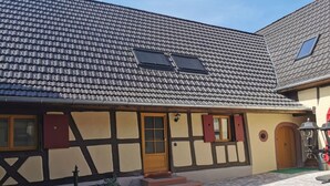 Una casa tradicional de entramado de madera con techo de tejas, puerta de madera y un pequeño jardín delantero.