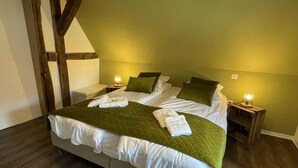 Una cama bien hecha con ropa de cama verde y almohadas blancas, dos lámparas de noche y un cabecero de madera.