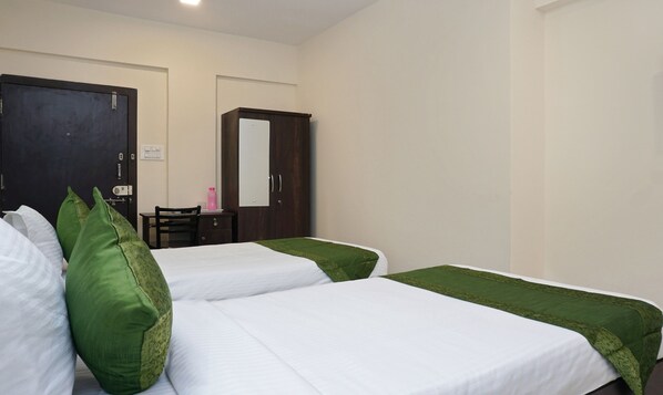 Una habitación de hotel con dos camas individuales, un escritorio, una silla, un armario y un espejo.