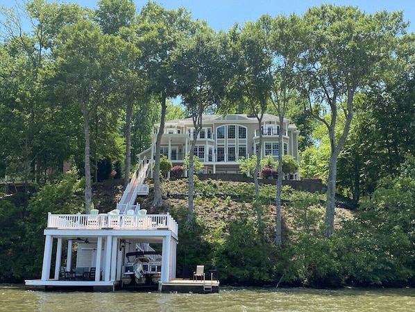 Ein großes Haus mit Anlegesteg und Boot, umgeben von Bäumen.