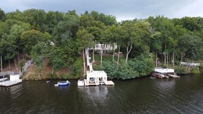 Ein Steg mit einem Haus und einem Boot, umgeben von dichtem Wald.