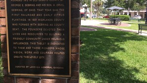 A historical plaque in a park with a bench and trees in the background. - Historic Section of Sebring  Townhome (Sebring)