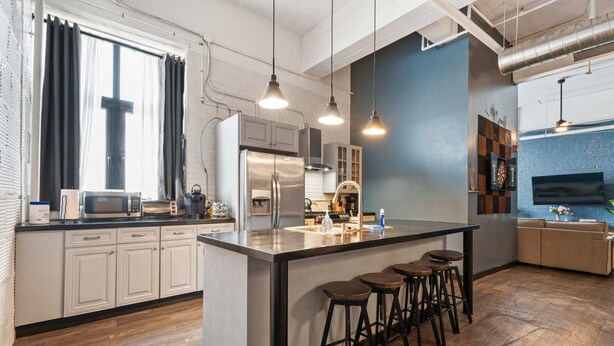 A modern kitchen with a central island, bar stools, and a large window with curtains. - *New* Huge!  Spacious 3 Bedroom in Oakland that sleeps 12! over 3000+ sq ft (Pittsburgh)