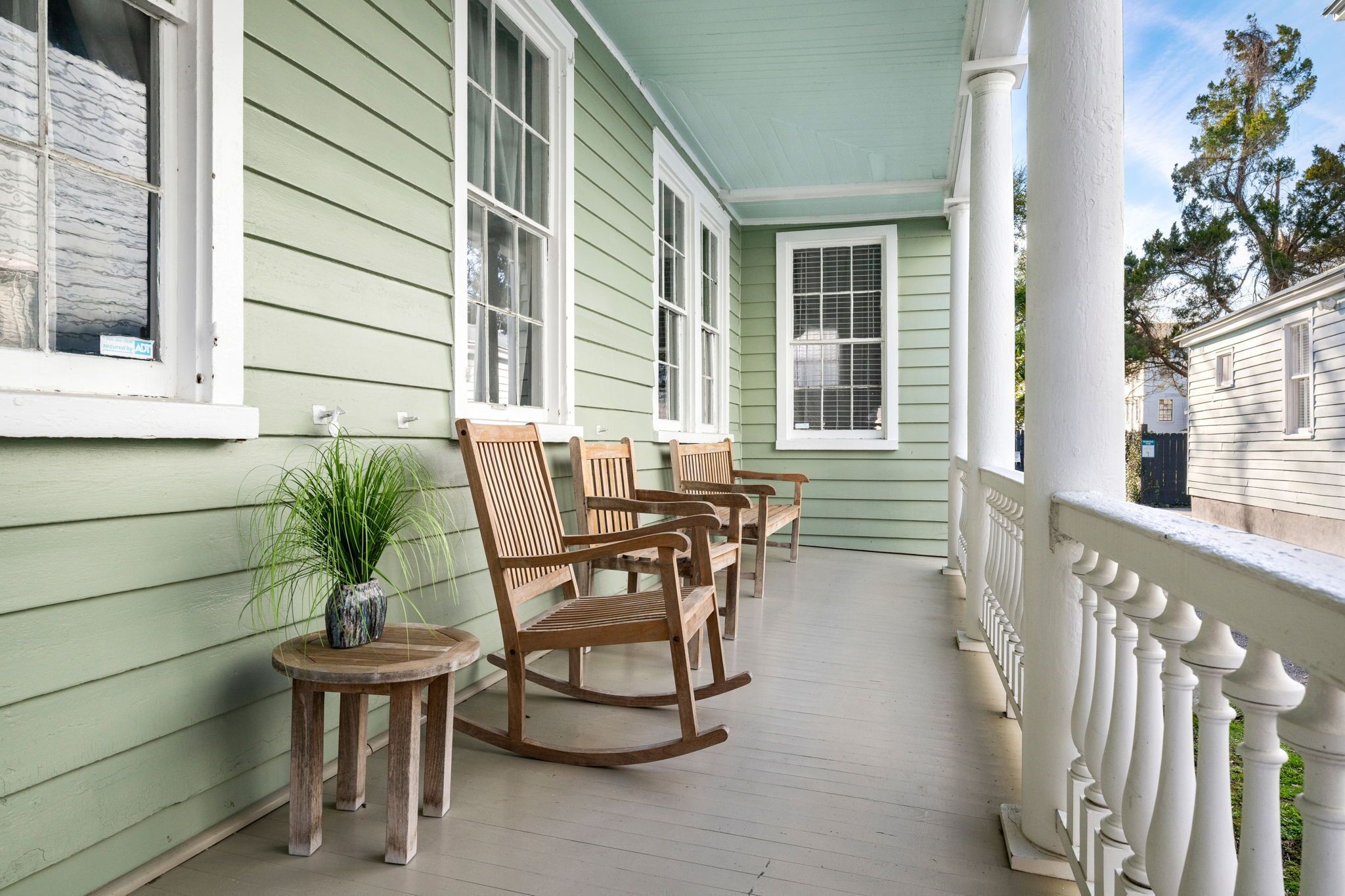 A porch with rocking chairs and a small table with a plant.