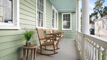 A porch with rocking chairs and a small table with a plant.