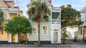 A historic building with a prominent palm tree in front, a balcony, and a white door with the number 77. - Great Neighborhood Restaurants | Lewis Court - A (Charleston)