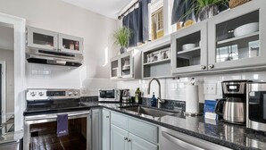 A modern kitchen with white cabinets, stainless steel appliances, and a granite countertop. - Great Neighborhood Restaurants | Lewis Court - A (Charleston)