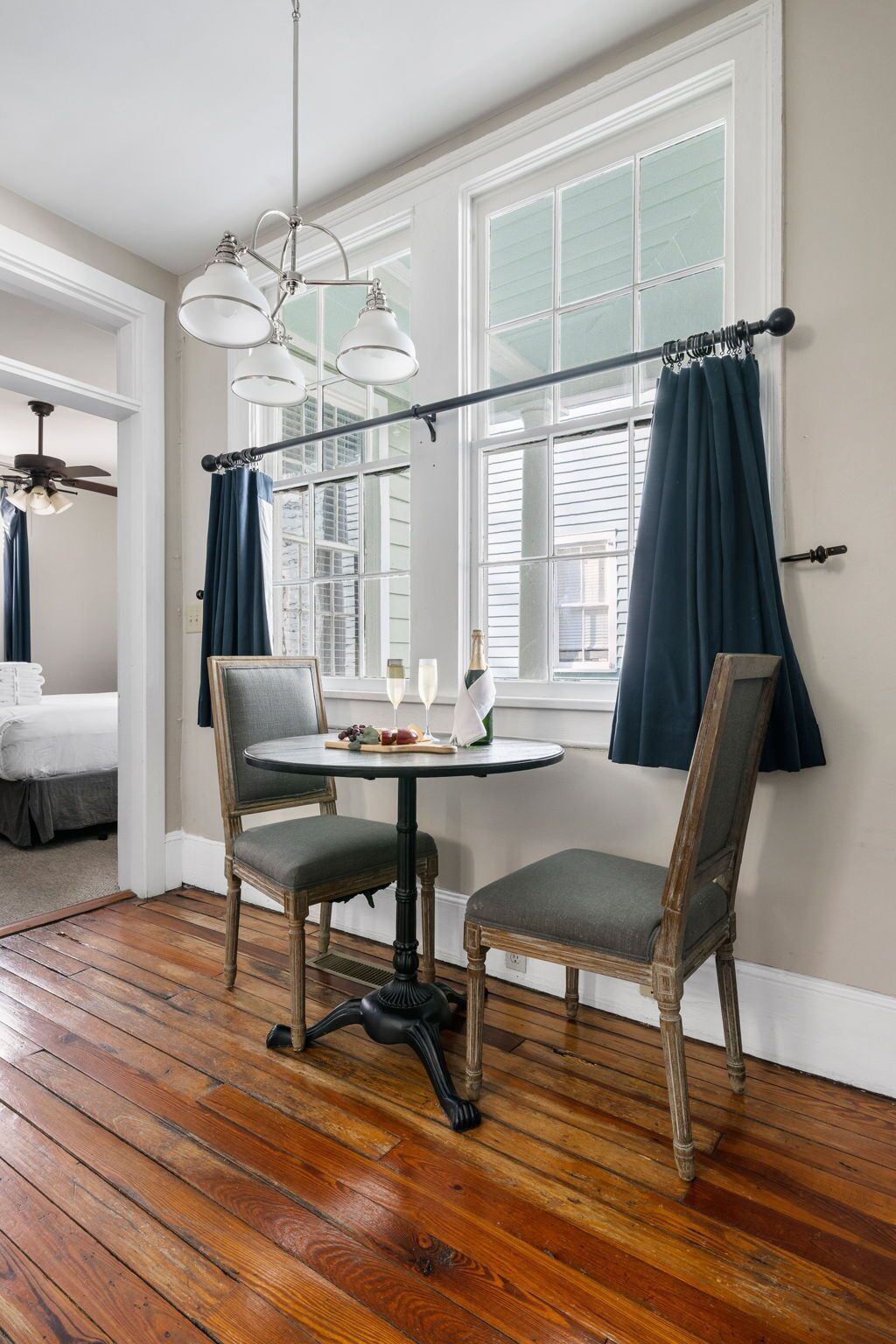 A dining area with a round table, two chairs, and a chandelier.