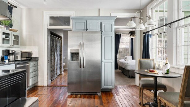 A modern kitchen with stainless steel appliances, wooden flooring, and a dining area with a table and chairs. - Great Neighborhood Restaurants | Lewis Court - A (Charleston)
