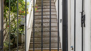 Une entrée fermée par un portail, avec un escalier en bois menant à un bâtiment.