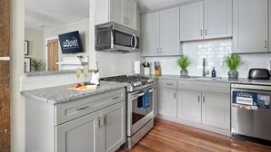 A modern kitchen with grey cabinets, a stainless steel stove, and a dishwasher.
