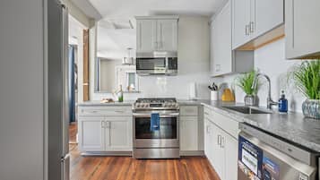 Une cuisine moderne dotée d’appareils électroménagers en acier inoxydable, de meubles blancs et d’un plancher en bois.