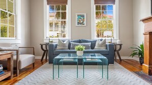 A living room with a sofa, two glass coffee tables, a side table, and a potted plant. - 3 Blocks to King, Historic Home | The Garden Gates (Charleston)