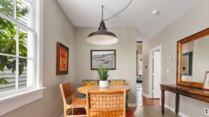 A dining area with a round table, wicker chairs, a potted plant, and a hanging light fixture. - 3 Blocks to King, Historic Home | The Garden Gates (Charleston)