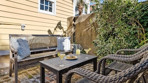 Eine Terrasse mit Korbmöbeln, einer Bank und einem Tisch mit Getränken und Snacks.