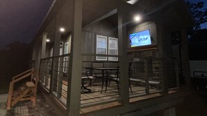 Een gebouw met twee verdiepingen, een balkon, een aan de muur bevestigde televisie en een houten trap naar de ingang.