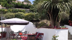 An outdoor patio area with a white umbrella, red chairs, a wooden barrel, and potted plants. - Charming Basque house with jacuzzi, close to the ocean (Saint-Jean-de-Luz)