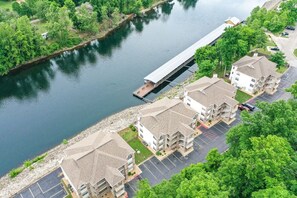 Área residencial com uma ponte sobre um rio, cercada por vegetação e um estacionamento.