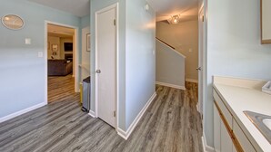 A hallway with a wooden floor, a door leading to a living room, and a staircase. - Short breaks in September and October live now! (Rehoboth Beach)