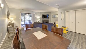 A spacious living room with a large wooden dining table, comfortable seating, a fireplace, and a television. - Short breaks in September and October live now! (Rehoboth Beach)
