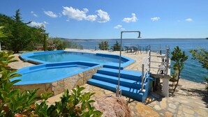 A swimming pool with a stone border and blue steps leading to a deck area with outdoor furniture. - 2-raum-apartment/studio , Adria Paradies - Direkt am Meer+privat (Starigrad Paklenica)