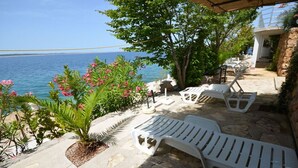 A terrace with white plastic lounge chairs, a stone pathway, and a view of the sea. - 2-raum-apartment/studio , Adria Paradies - Direkt am Meer+privat (Starigrad Paklenica)