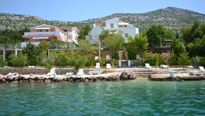 A coastal hotel with multiple buildings, a rocky shoreline, and a mountain in the background. - 2-raum-apartment/studio , Adria Paradies - Direkt am Meer+privat (Starigrad Paklenica)