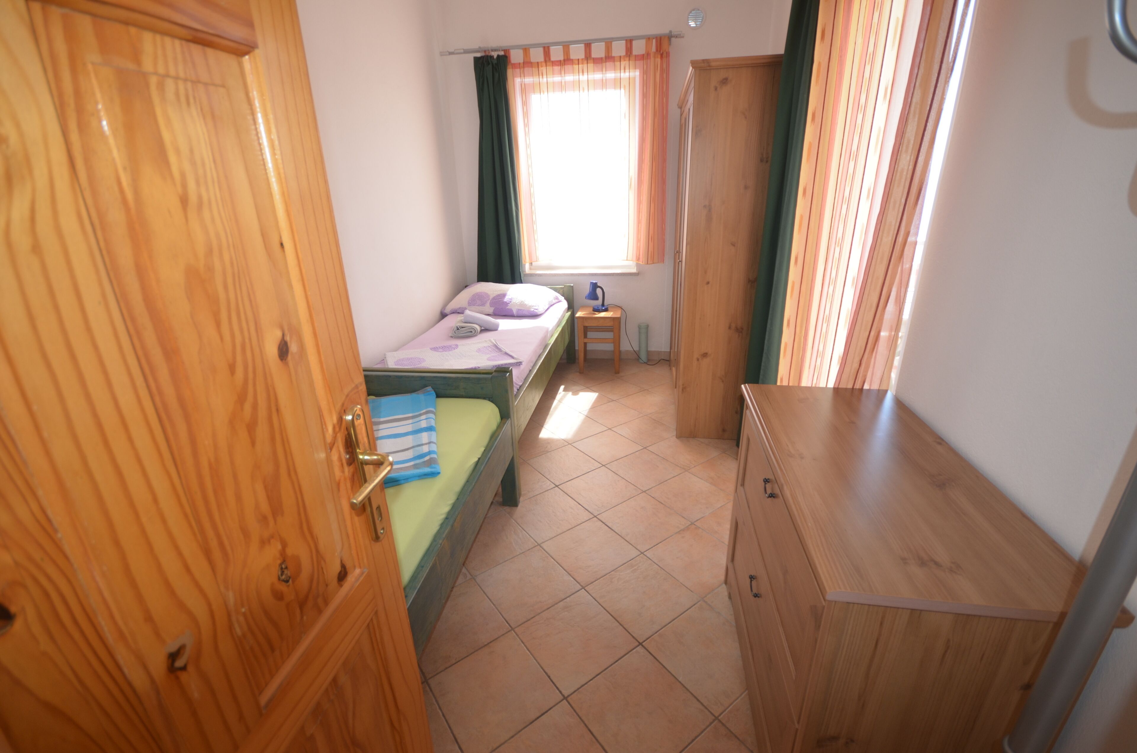 A room with a bed, a desk, a wardrobe, and a window with curtains.