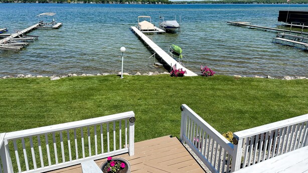 Une jetée au bord du lac avec des bateaux, une zone herbeuse et une terrasse en bois dotée d’une rambarde.