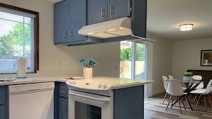 Une cuisine moderne équipée d’un lave-vaisselle, d’une cuisinière et d’un coin repas avec des chaises et une table.