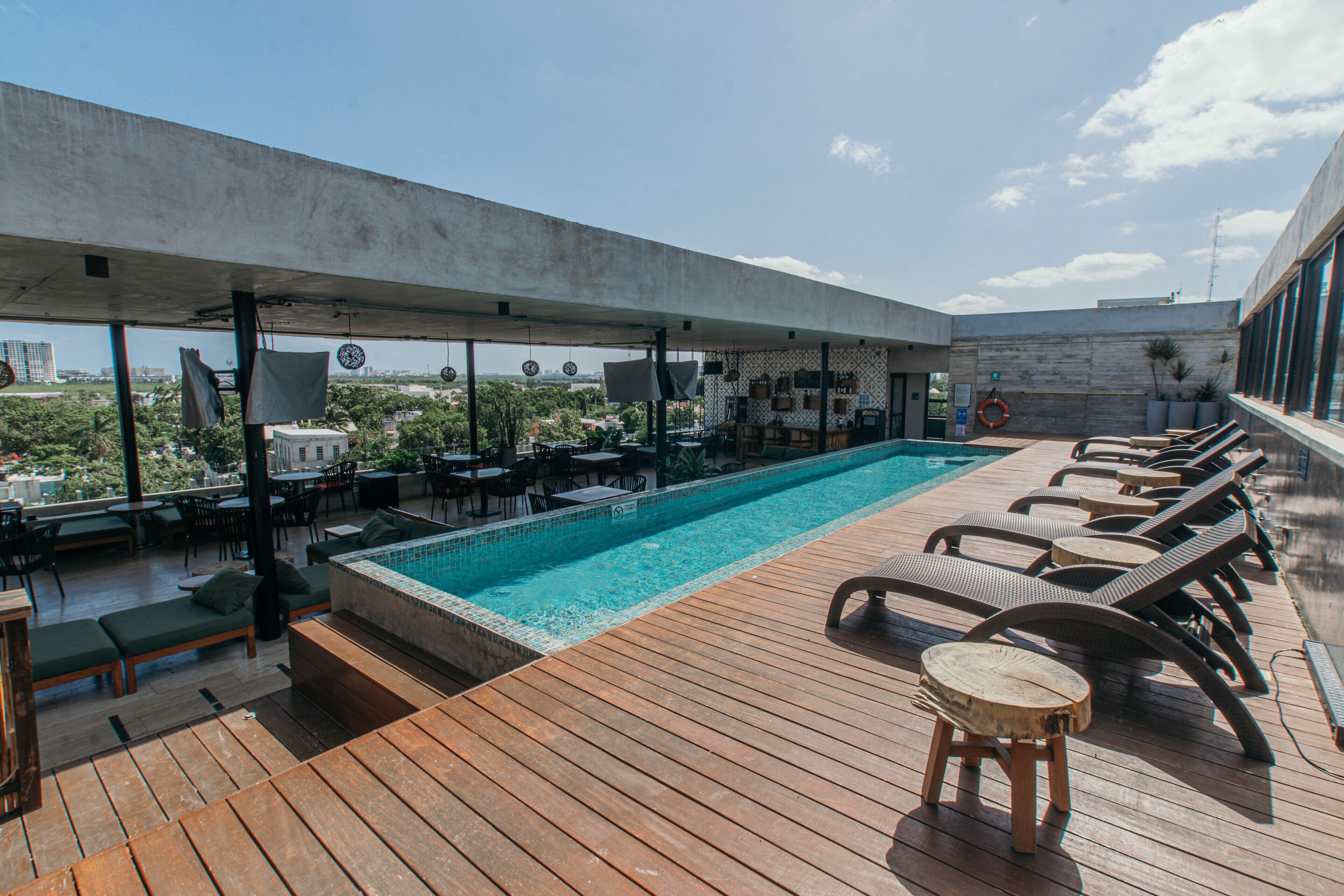 Un área de piscina en la azotea con sillones de descanso, un jacuzzi y vistas a la ciudad.
