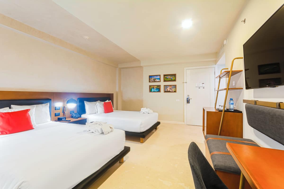 Une chambre d’hôtel avec deux lits, un bureau, une chaise, une télévision et une porte.