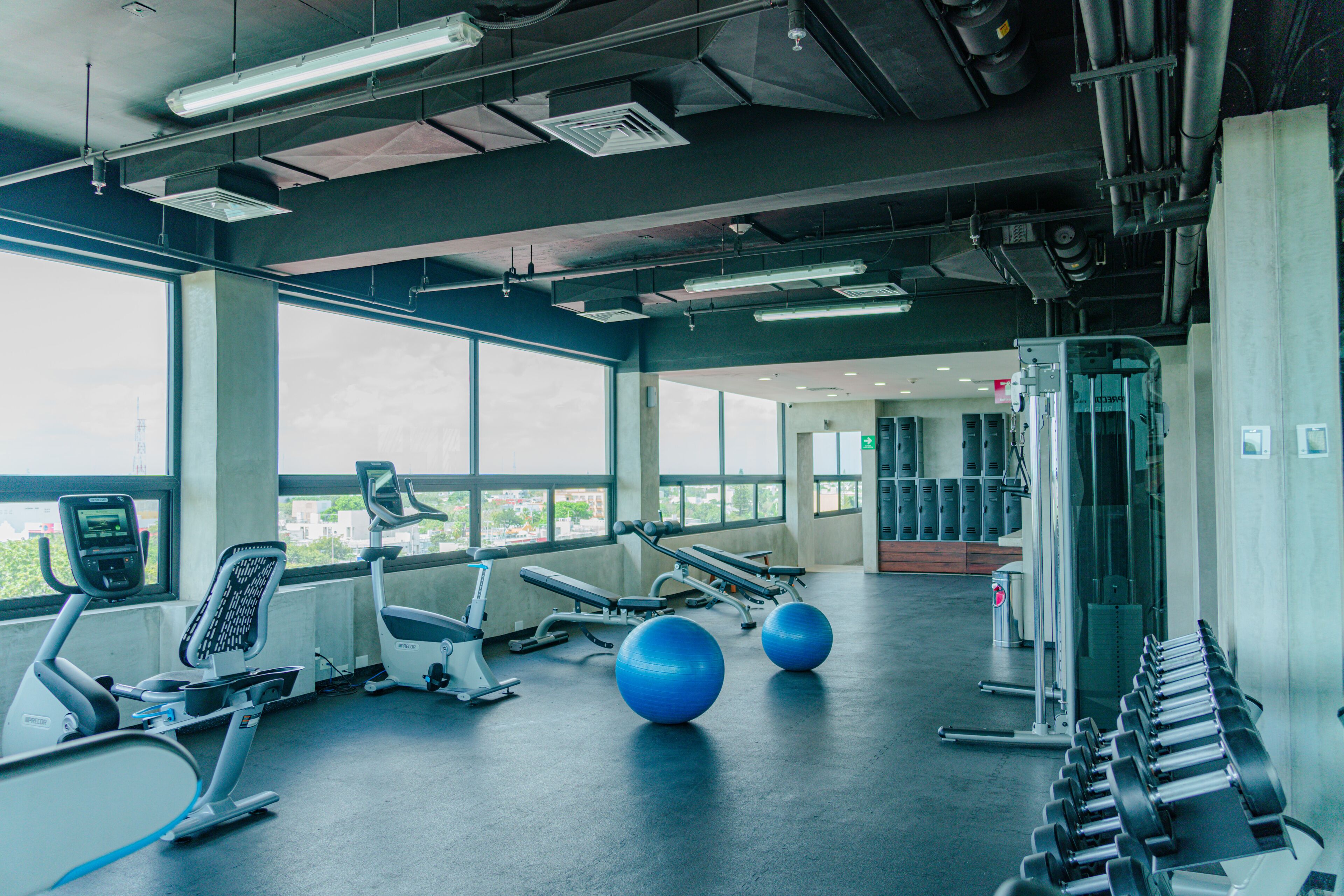 A gym with exercise equipment, large windows, and a view of the city.