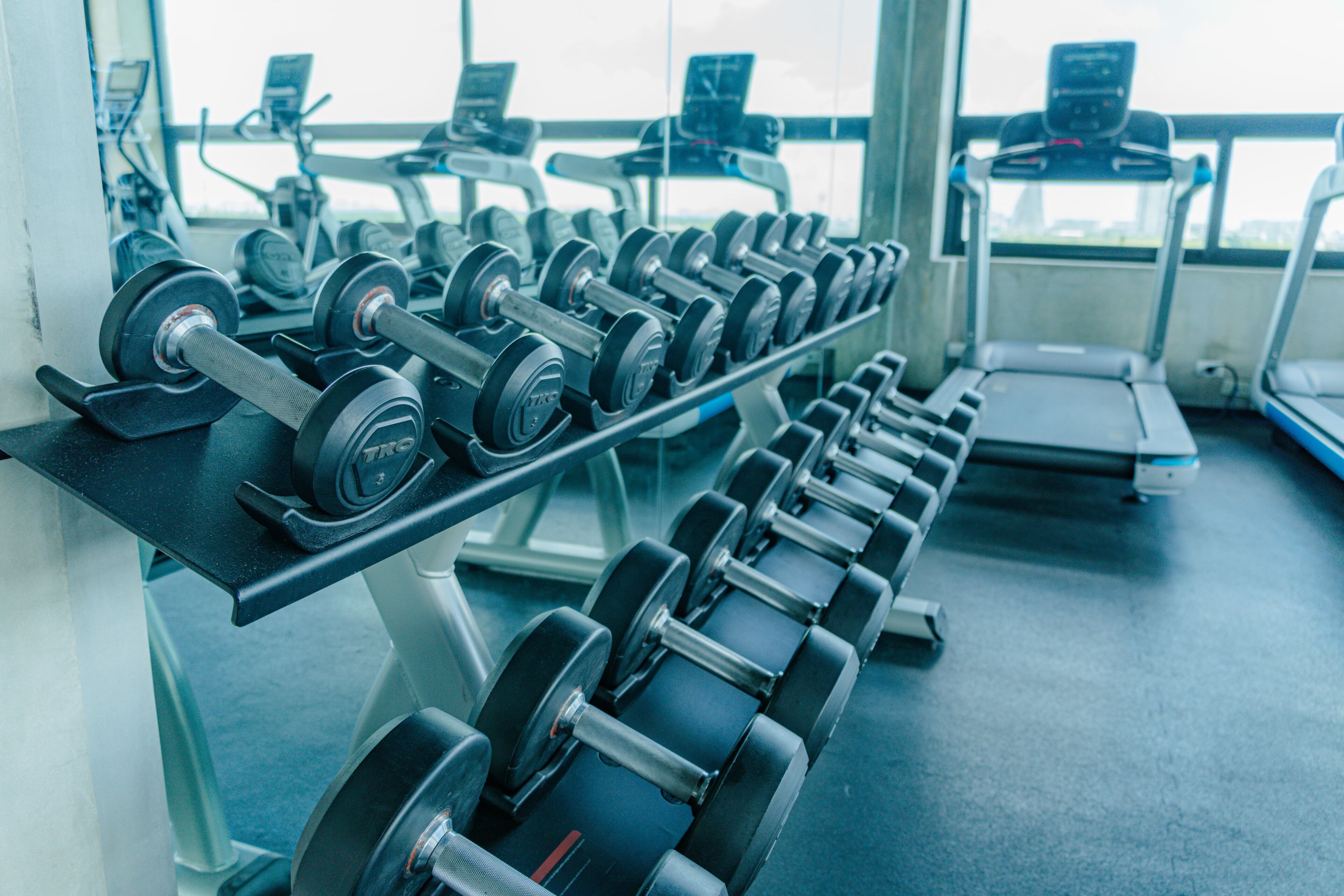 Un gimnasio con filas de mancuernas y cintas de correr.