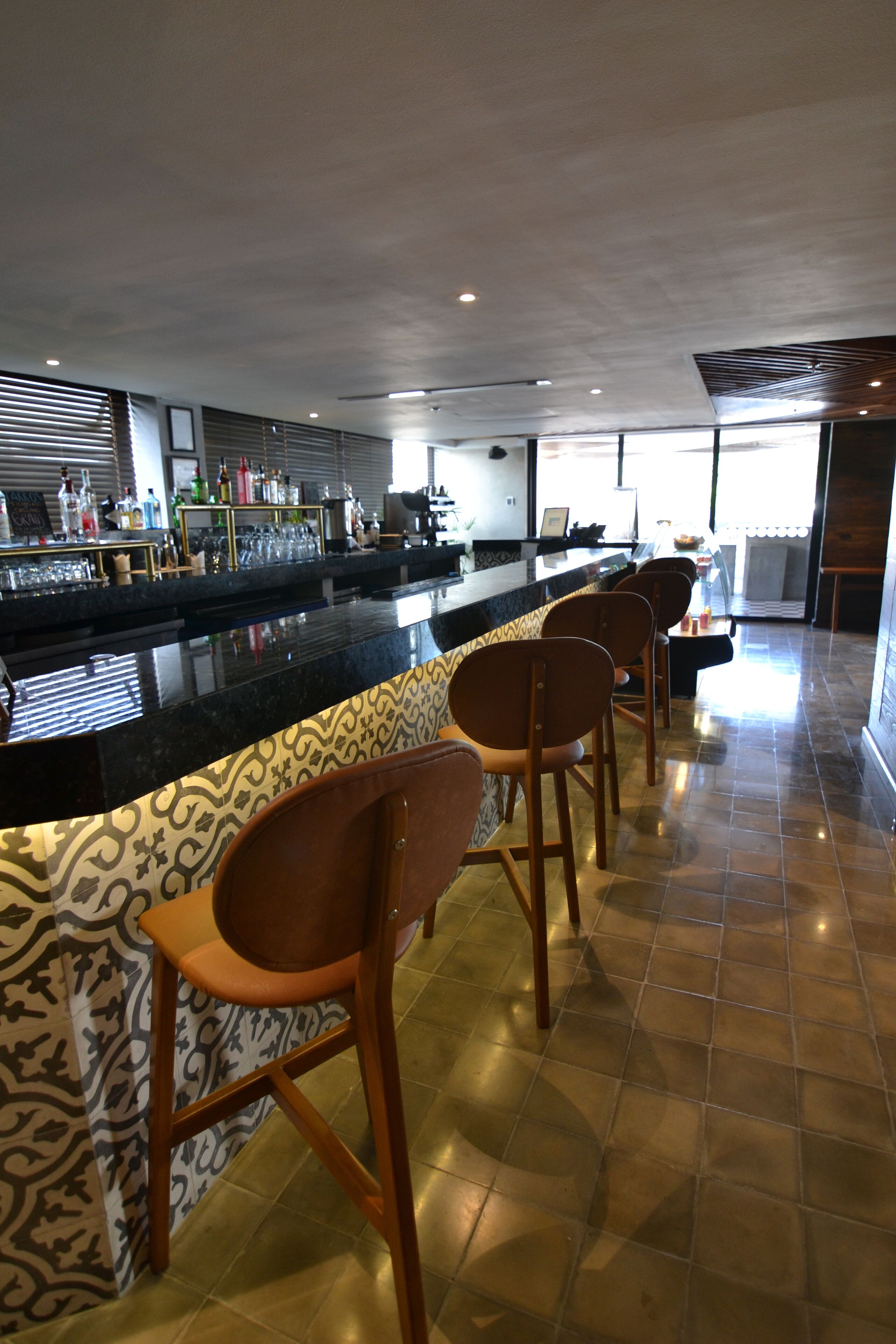 A bar area with a counter, bar stools, and a patterned wall.